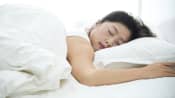 Woman sleeping on her stomach in a bed