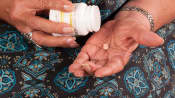 Elderly woman emptying pill from pill bottle in their hand