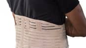 Man&#039;s torso with a lower back brace over his shirt