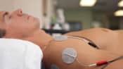 Electotherapy unit attached to a patient&#039;s shoulder.