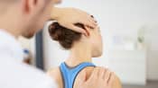 Male physical therapist massaging a young woman&#039;s neck in the medical office