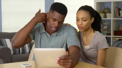 A man reading a tablet while pointing at the pain in his neck