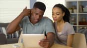 Young man holding his neck and reading a tablet with his girlfriend
