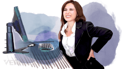 Woman siting by a desk and holding her lower back in pain.