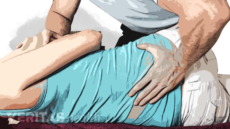 Photo of a chiropractor performing a lumbar adjustment on a woman.